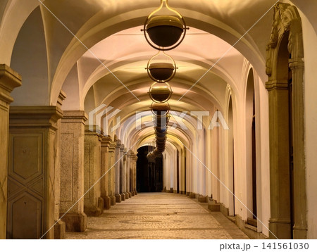 Elegant old hallway. Historic arched corridor adorned with glowing lamps and polished stone surface 141561030