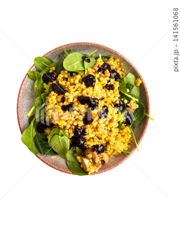 Colorful salad with yellow grains, spinach leaves, and dark berries served in a round ceramic bowl on a white background Colorful salad with yellow grains, spinach leaves, and dark berries served in a round ceramic bowl on a white background 141561068