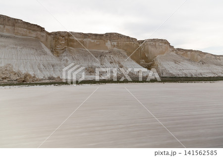 White chalk cliffs along a sandy beach under a cloudy sky White chalk cliffs along a sandy beach under a cloudy sky 141562585