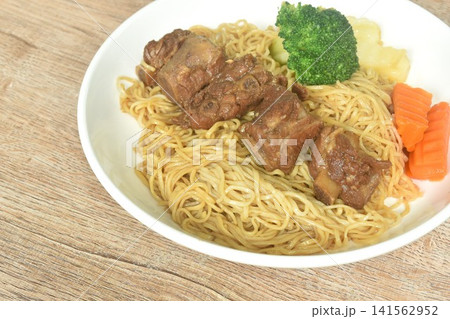 Chinese yellow egg nodles topping braised slice honey pork bone stew dressing black herb sauce with boiled vegetable on plate Chinese yellow egg nodles topping braised slice honey pork bone stew dressing black herb sauce with boiled vegetable on plate 141562952