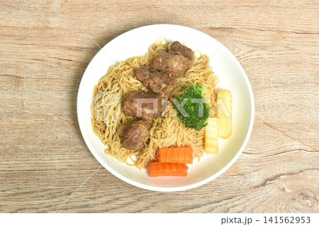 Chinese yellow egg nodles topping braised slice honey pork bone stew dressing black herb sauce with boiled vegetable on plate Chinese yellow egg nodles topping braised slice honey pork bone stew dressing black herb sauce with boiled vegetable on plate 141562953