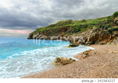 Dramatic coastal cliffs meet a turbulent sea under an overcast sky Dramatic coastal cliffs meet a turbulent sea under an overcast sky 141563217