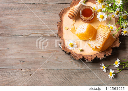 Golden honeycomb on wooden slept with chamomile flowers, fresh honey Golden honeycomb on wooden slept with chamomile flowers, fresh honey 141563925