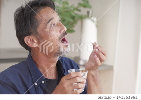 内服薬を飲もうとするシニア男性 内服薬を飲もうとするシニア男性 141563963