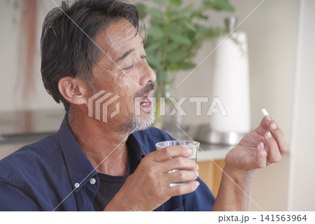 内服薬を飲もうとするシニア男性 141563964