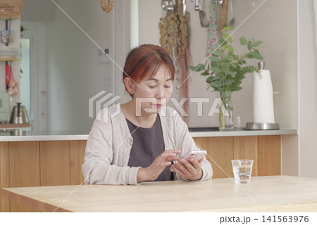 明るい室内でスマホを操作するシニア女性 141563976