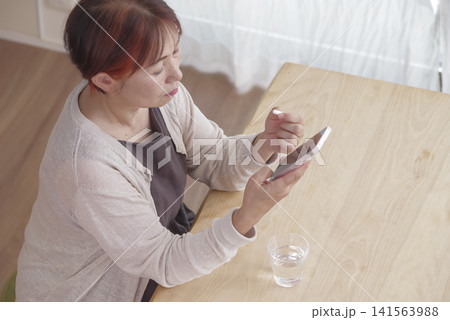 スマホと錠剤を手に健康管理をする女性 スマホと錠剤を手に健康管理をする女性 141563988