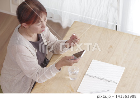 スマホと錠剤を手に健康管理をする女性 141563989