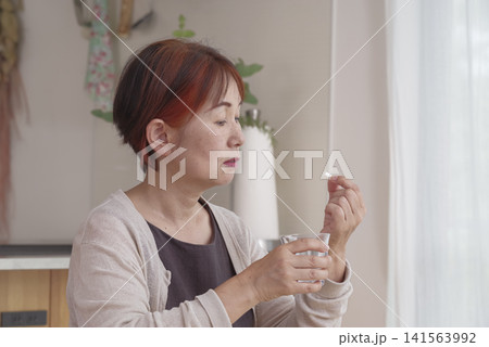 内服薬を飲もうとするシニア女性 141563992