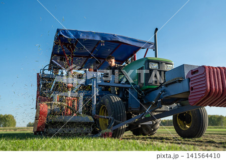 A Farm Tractor is Actively Working in the Open Field Beneath a Clear Blue Sky Above A Farm Tractor is Actively Working in the Open Field Beneath a Clear Blue Sky Above 141564410