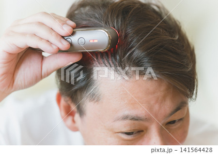 電気ブラシで頭をケアする40代男性 141564428