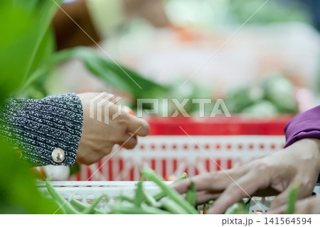 Closeup of hands selecting fresh green vegetables at a market stall 141564594