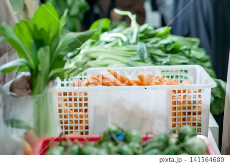 Closeup of hands selecting fresh green beans at a local farmers market, with blurred vegetable crates in the background, representing healthy eating and shopping Closeup of hands selecting fresh green beans at a local farmers market, with blurred vegetable crates in the background, representing healthy eating and shopping 141564680