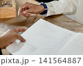 A close-up capture of a traditional wedding ceremony moment, highlighting the groom seated beside the officiant  141564887
