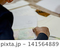 A close-up capture of a traditional wedding ceremony moment, highlighting the groom seated beside the officiant  141564889