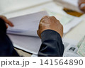 A close-up capture of a traditional wedding ceremony moment, highlighting the groom seated beside the officiant  141564890