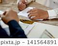 A close-up capture of a traditional wedding ceremony moment, highlighting the groom seated beside the officiant  141564891