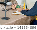 A close-up capture of a traditional wedding ceremony moment, highlighting the groom seated beside the officiant  141564896