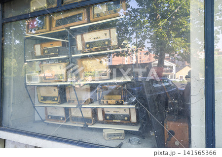 A collection of vintage radios displayed on shelves behind a window. A collection of vintage radios displayed on shelves behind a window. 141565366