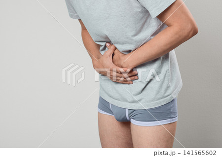 Man holding his painful stomach due to acute gastritis and peptic ulcer. Gastroenterology diagnostic consultation and abdominal pain treatment. 141565602