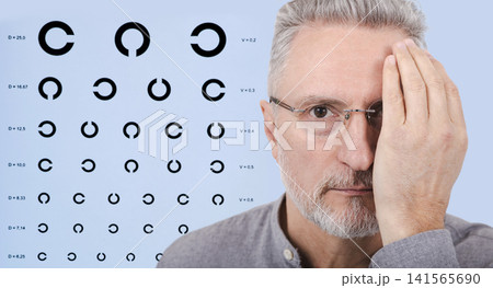 Senior man covering one eye with his hand for monocular vision testing during an ophthalmology diagnostic consultation. Senior man covering one eye with his hand for monocular vision testing during an ophthalmology diagnostic consultation. 141565690