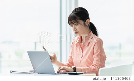 パソコンとスマートフォンを使う女性・ビジネスウーマン パソコンとスマートフォンを使う女性・ビジネスウーマン 141566468