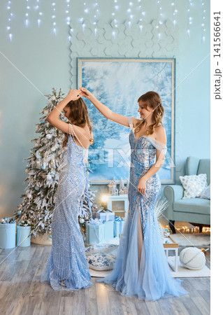 woman and a young girl dressed in matching elegant light-blue sequined gowns, standing together in a woman and a young girl dressed in matching elegant light-blue sequined gowns, standing together in a 141566641
