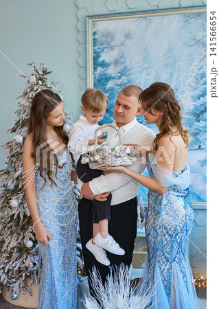 medium shot photograph of a family gathered together in a light-blue studio decorated with frosted 141566654