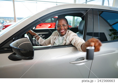 Happy black woman showing car key inside new vehicle Happy black woman showing car key inside new vehicle 141566663
