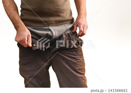 Man pulling pants over thermal leggings, adjusting for warmth and comfort. Man pulling pants over thermal leggings, adjusting for warmth and comfort. 141566681