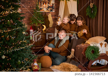 family of four dressed in matching brown sweaters, gathered together in a rustic room with a exposed 141566713