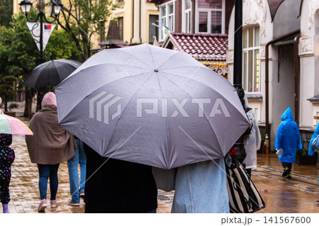 Portrait of person holding black umbrella outside during the rain. Rainy weather and forecast concept Portrait of person holding black umbrella outside during the rain. Rainy weather and forecast concept 141567600
