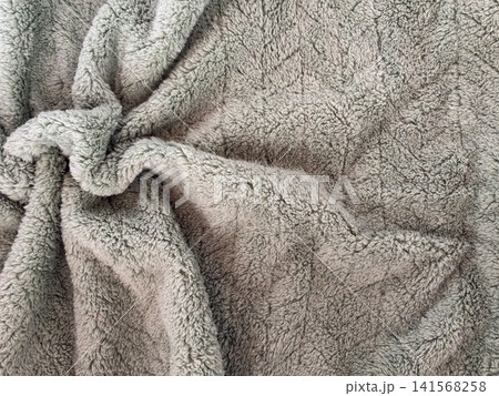 Soft gray fleece blanket with fluffy plush texture and natural folds, suitable as cozy textile background for home comfort, warmth, winter lifestyle, bedding, fabric, and interior design concepts. 141568258