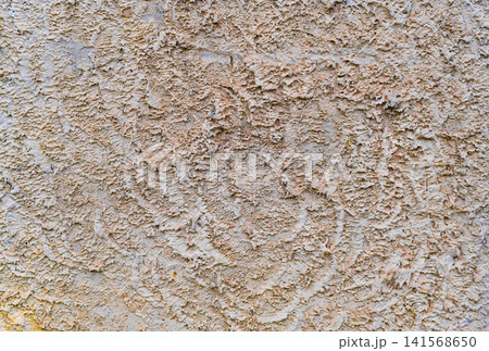Weathered concrete wall demonstrates rough beige plaster texture with embossed details. Weathered concrete wall demonstrates rough beige plaster texture with embossed details. 141568650
