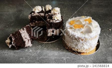 Delicious chocolate cake and sweet coconut treat placed on dark counter. Delicious chocolate cake and sweet coconut treat placed on dark counter. 141568814