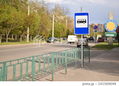 Bus stop sign near urban road with sidewalk barrier and traffic. 141569049