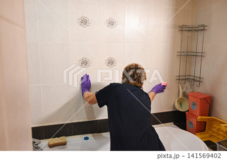 Woman cleaning tiles in a bathroom during daylight 141569402