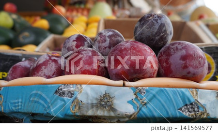 Red plums centered on decorated tray contrasting background fruits Red plums centered on decorated tray contrasting background fruits 141569577