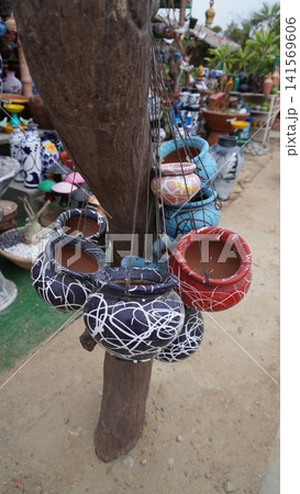 Colorful painted pots hang from wooden tree like trunk Colorful painted pots hang from wooden tree like trunk 141569606