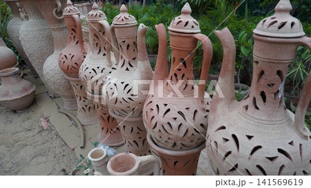 Ornate earthenware pitchers with cutouts aligned in row Ornate earthenware pitchers with cutouts aligned in row 141569619