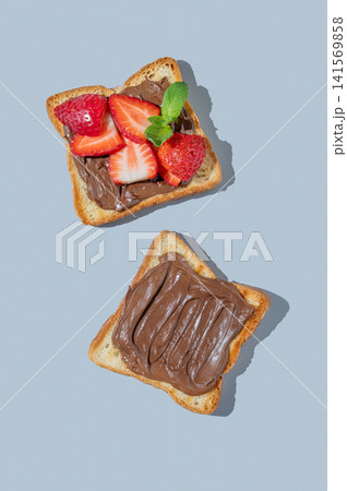 Two toasted slices with chocolate cream and strawberries on a blue isolated background Two toasted slices with chocolate cream and strawberries on a blue isolated background 141569858