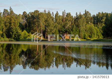 Calm lake mirrors forested shoreline at golden hour Calm lake mirrors forested shoreline at golden hour 141570013