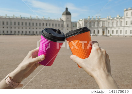 Two hands hold bright coffee cups in a toast Two hands hold bright coffee cups in a toast 141570039