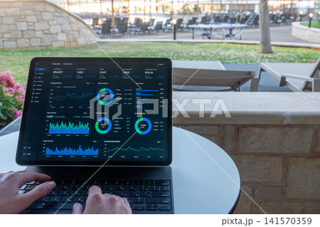Hands Typing on Tablet with Financial Dashboard at Resort Outdoor Terrace Hands Typing on Tablet with Financial Dashboard at Resort Outdoor Terrace 141570359