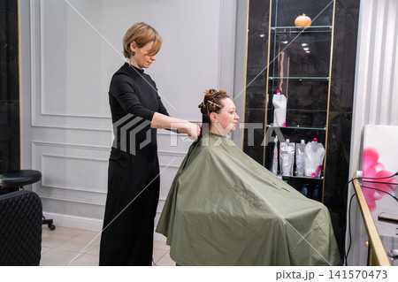 Young female hairdresser stylist working with scissors in beauty salon Stock Photo 141570473