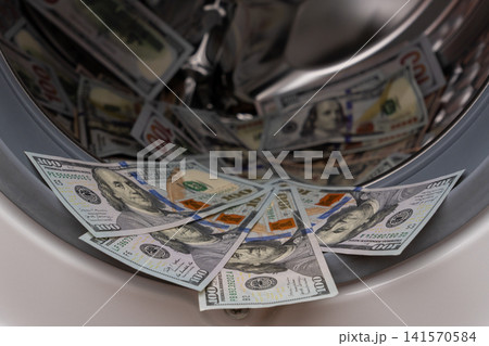 One hundred dollar bills inside open washing machine drum closeup One hundred dollar bills inside open washing machine drum closeup 141570584