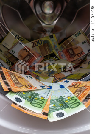 Euro banknotes inside open washing machine drum closeup Euro banknotes inside open washing machine drum closeup 141570596