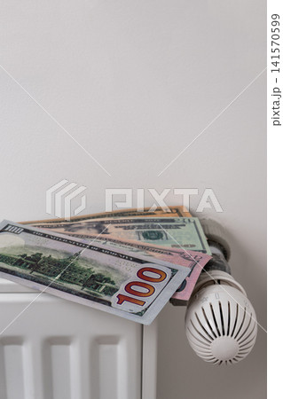 US dollar banknotes on central heating radiator with thermostat valve US dollar banknotes on central heating radiator with thermostat valve 141570599