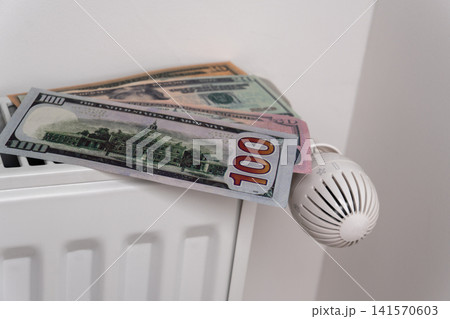 US dollar banknotes on central heating radiator with thermostat valve US dollar banknotes on central heating radiator with thermostat valve 141570603