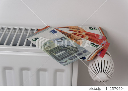 Euro banknotes on central heating radiator with thermostat valve 141570604
